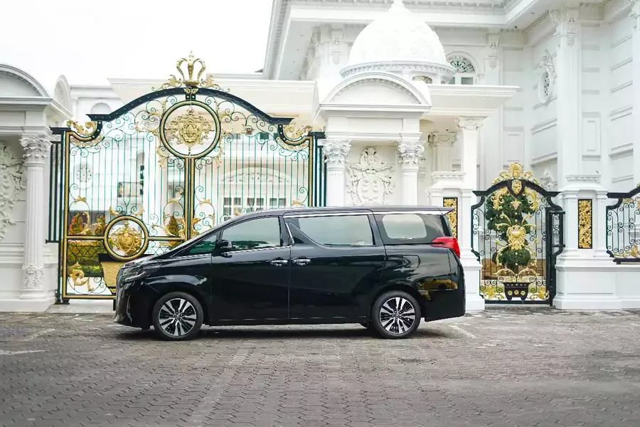 Black Toyota Alphard waiting side-on at an ornate gate