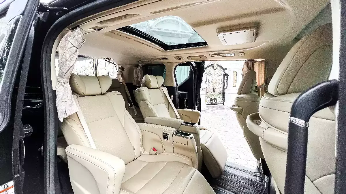 Cream leather captain's chairs seen through the open sliding door of a Toyota Alphard