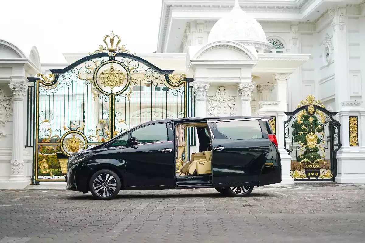 Black Toyota Alphard side-on with the passenger sliding door open at an ornate gate