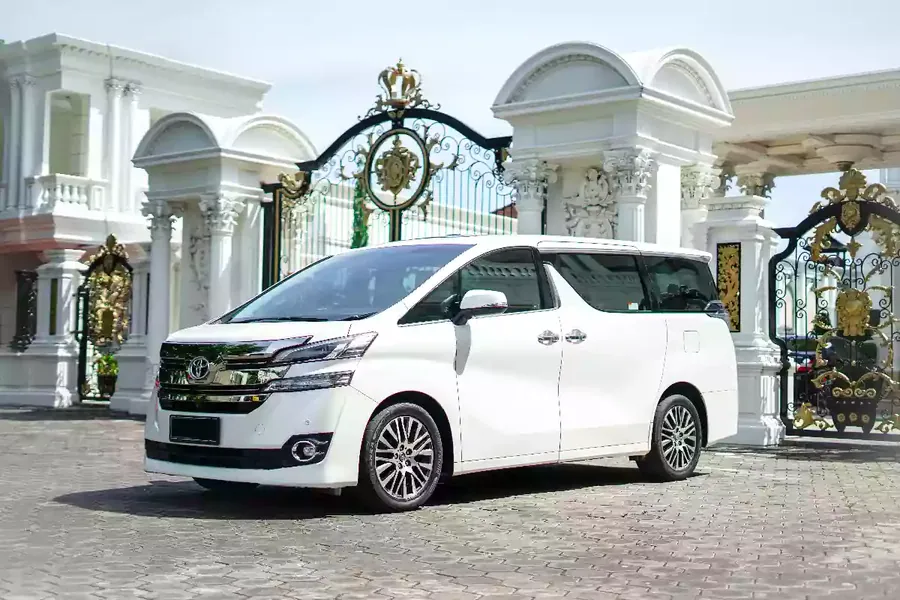 White Toyota Vellfire waiting side-on at an ornate gate