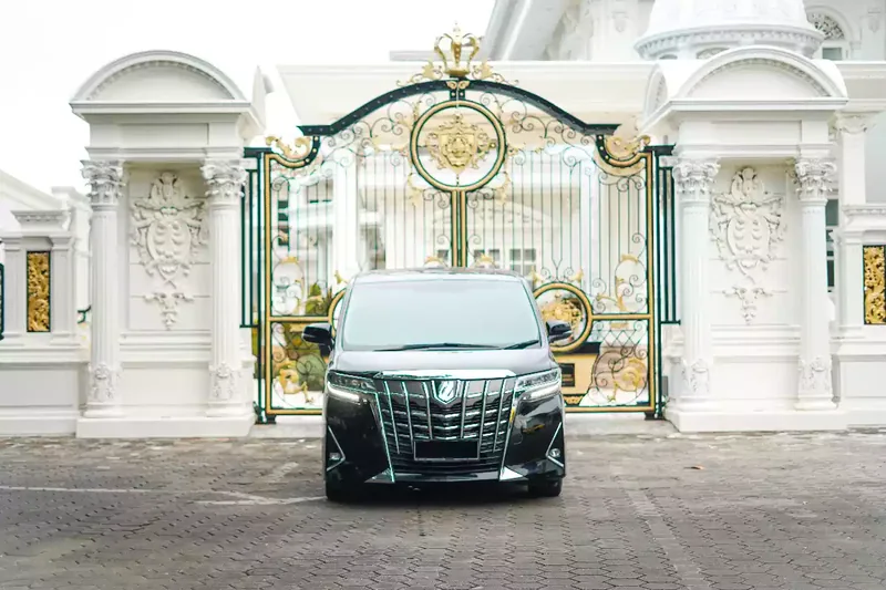 Black Toyota Alphard photographed head-on at a gate