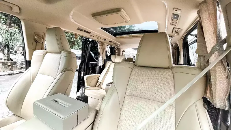 Alphard rear cabin with cream seats and bottled water to hand