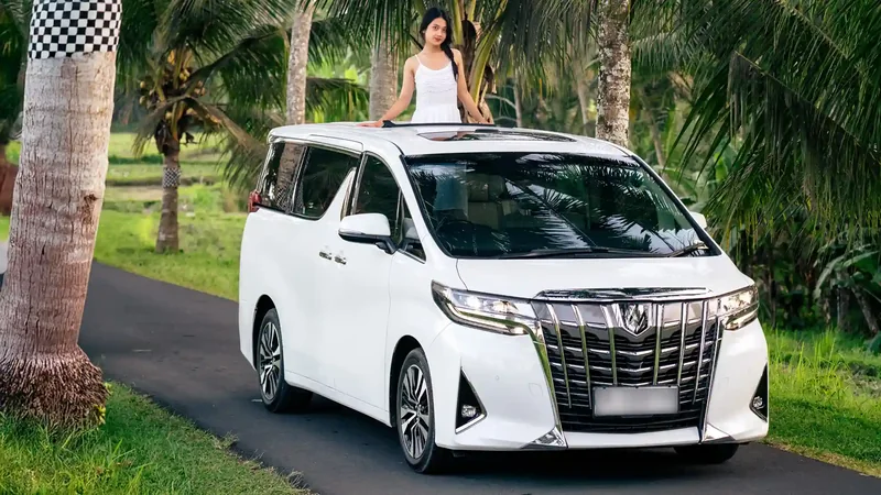 White Toyota Alphard on a palm-lined road