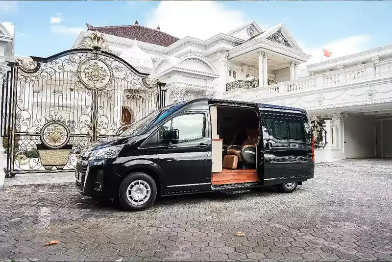 Black Toyota Hiace with its side door open at a gate