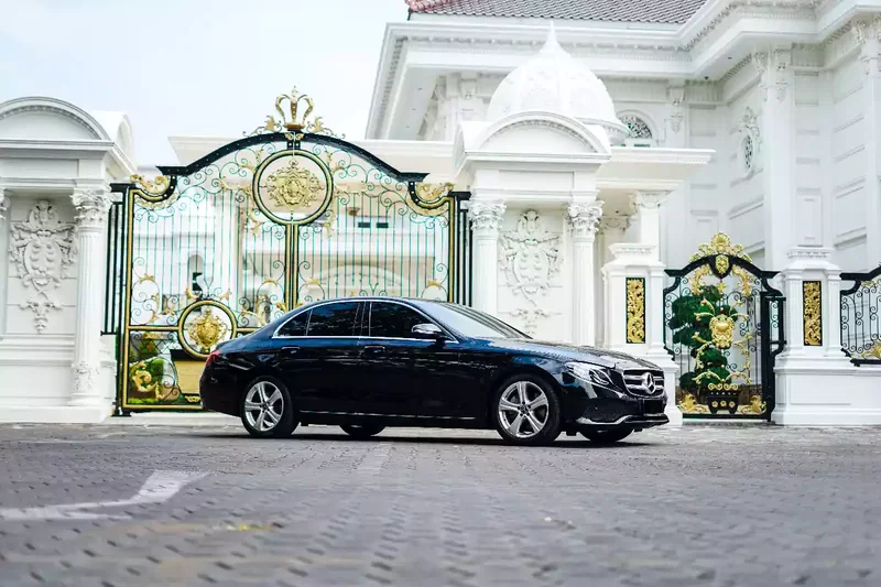 Black Mercedes-Benz saloon waiting at a gate