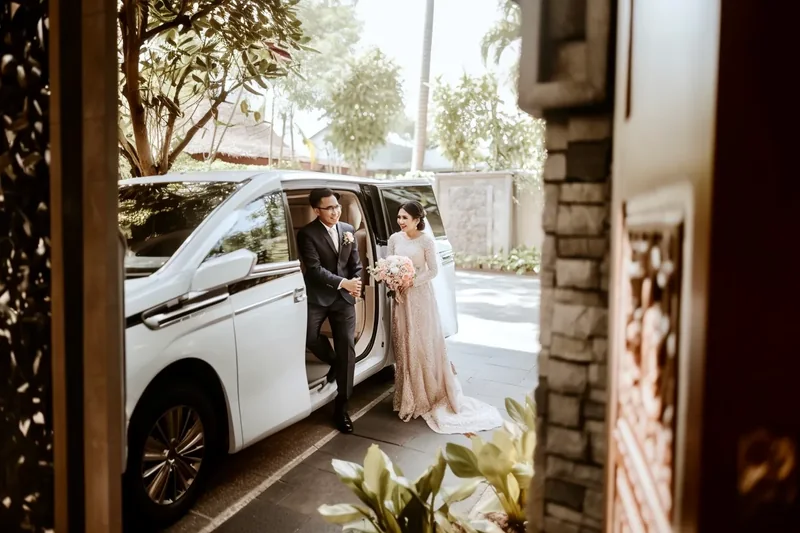 Couple stepping out of a white MPV at a wedding venue