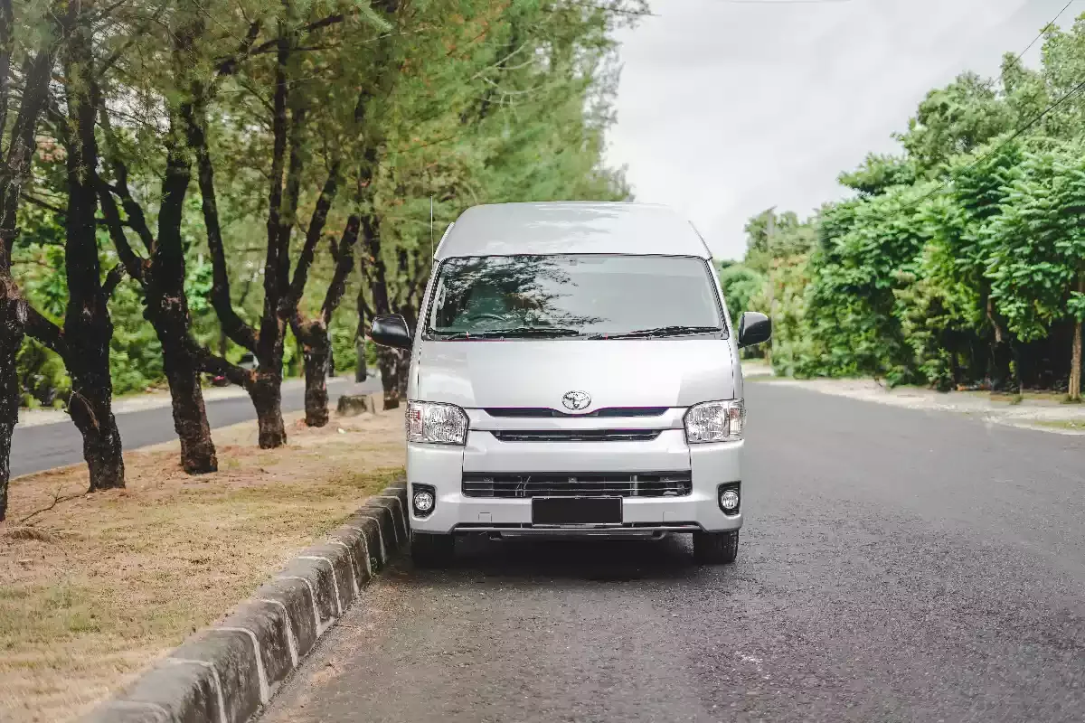 White Toyota Hiace Premio on an open tree-lined road