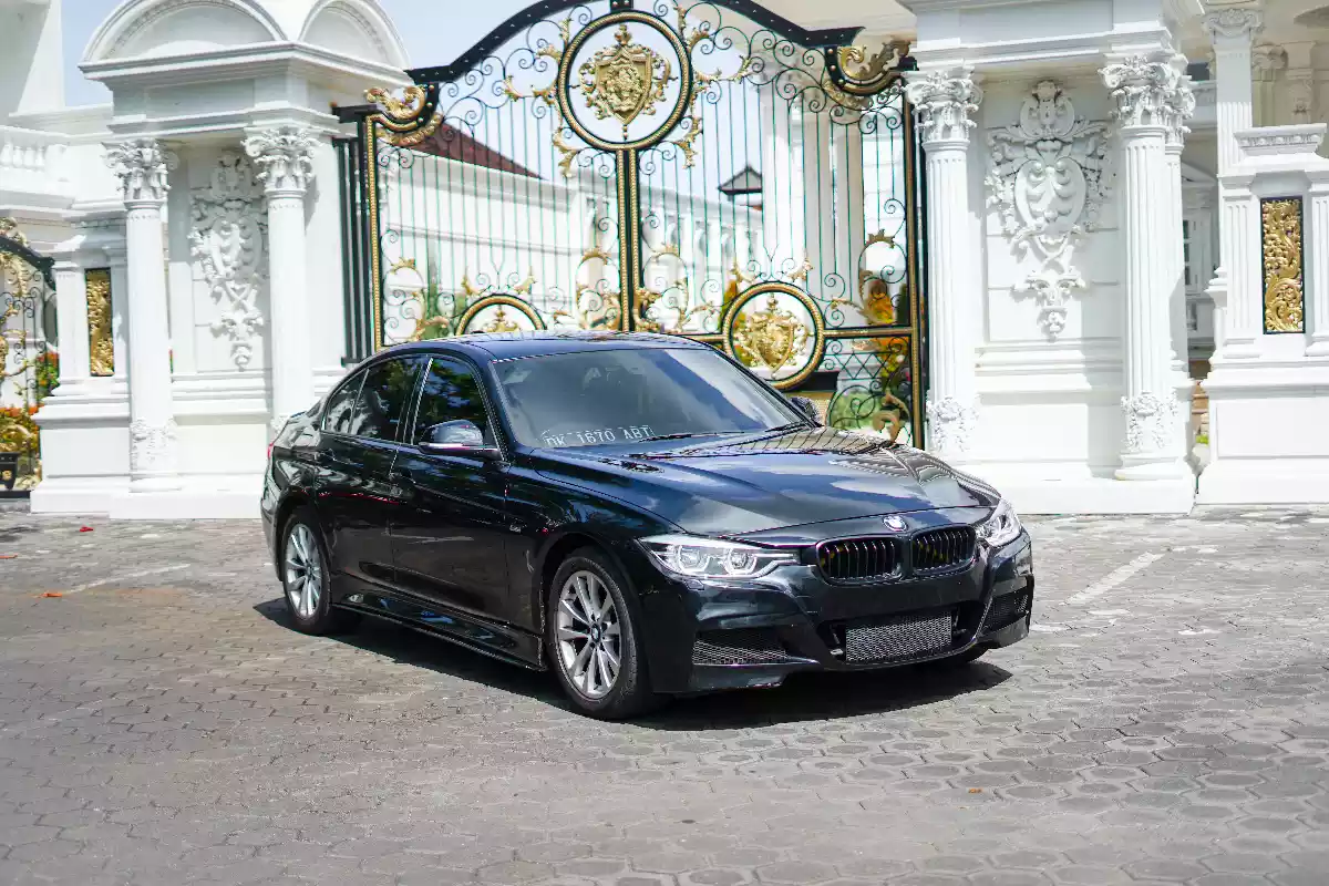 Black BMW saloon parked at a gate, front three-quarter view