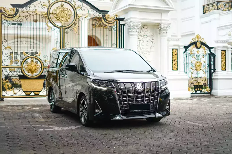 Black Toyota Alphard photographed head-on at a gate